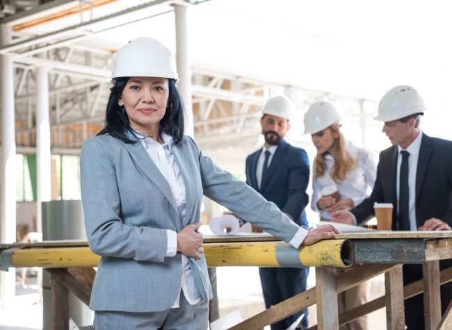 middle aged asian contractor looking at camera during meeting at construction site