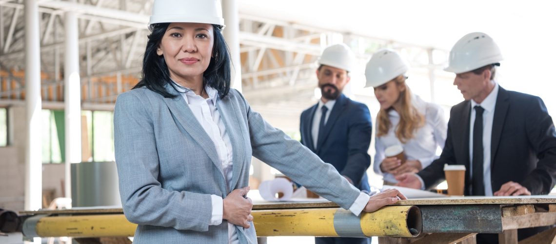 middle aged asian contractor looking at camera during meeting at construction site